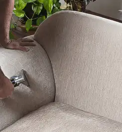Professional upholstery cleaner deep-cleaning a fabric sofa with a handheld extraction tool and hose Eugene, OR.